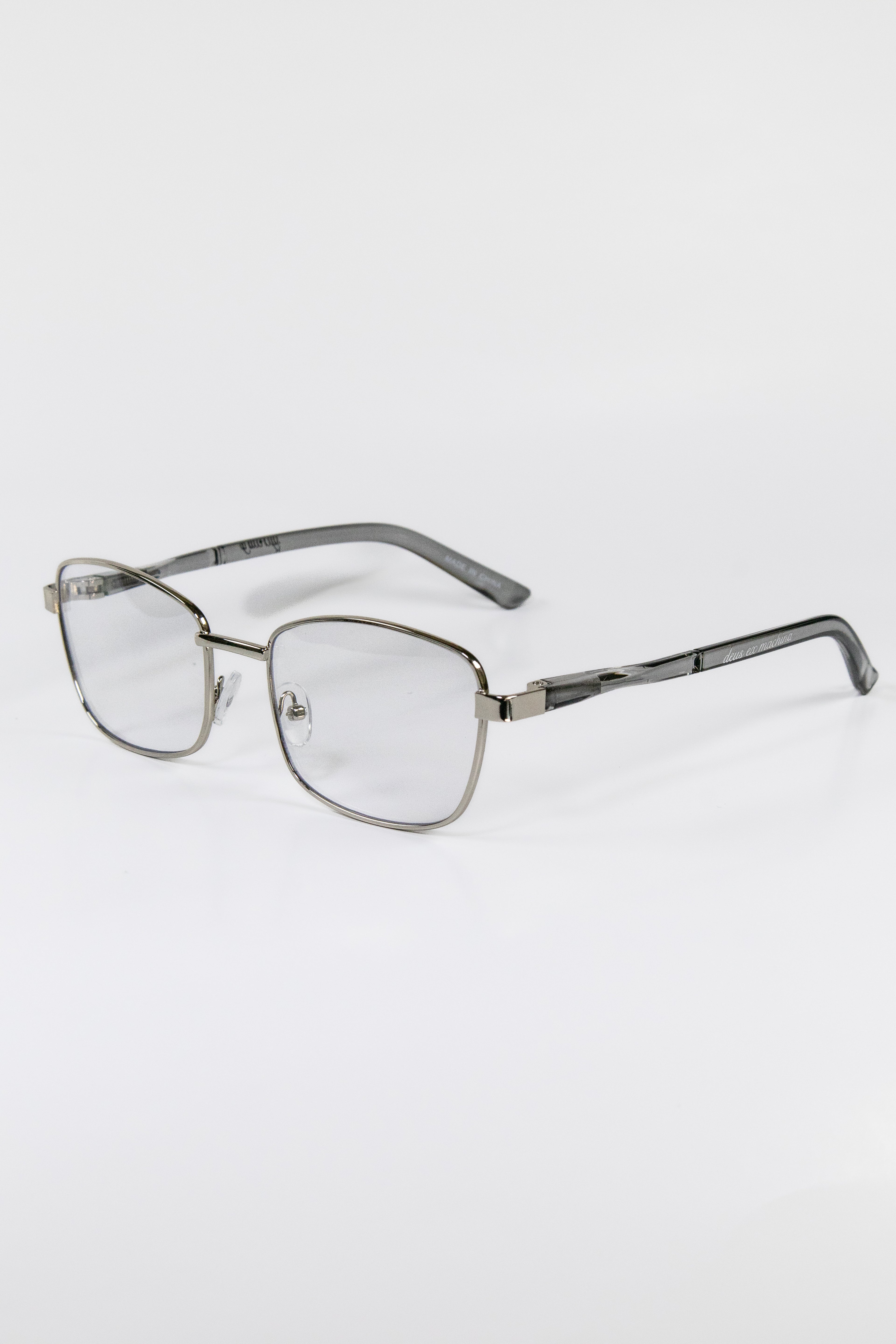 A pair of silver metal framed eyeglasses with a cat eye lens design, featuring a flexible silicone pad and spring hinges.