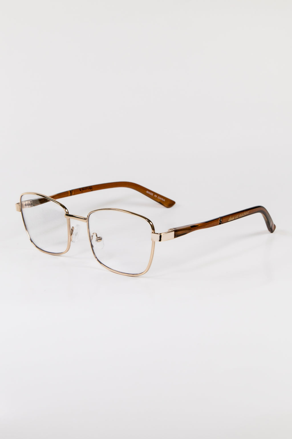 A pair of gold metal framed glasses with cat eye lenses and brown hinges