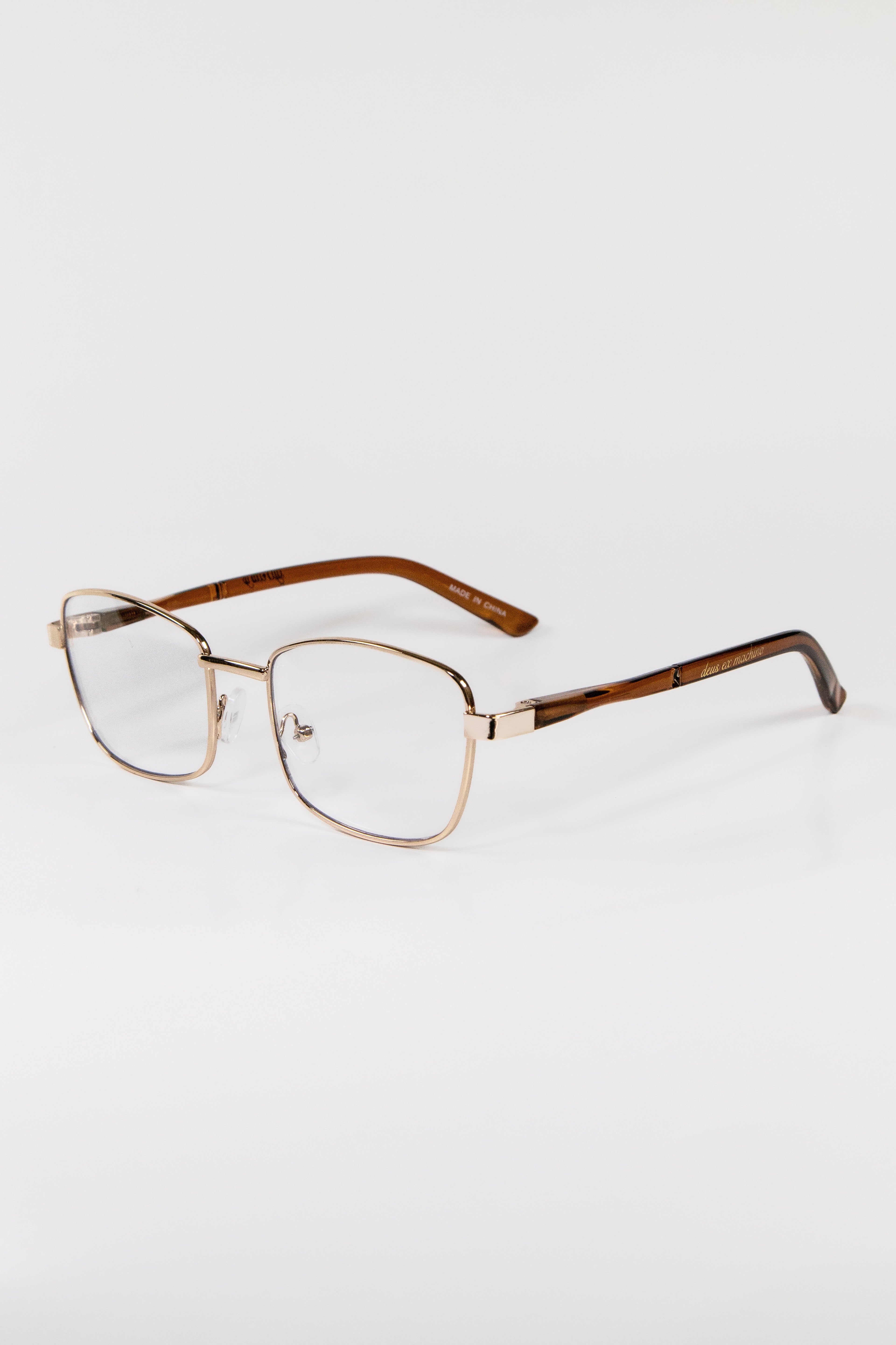 A pair of gold metal framed glasses with cat eye lenses and brown hinges