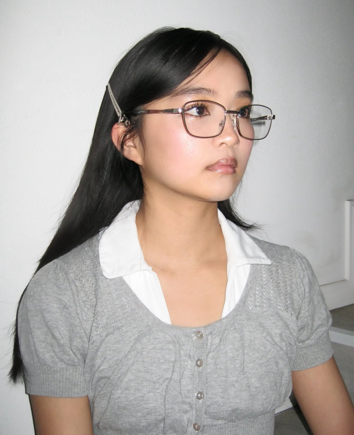 A woman wearing metal frame glasses with cat eye lenses wearing grey