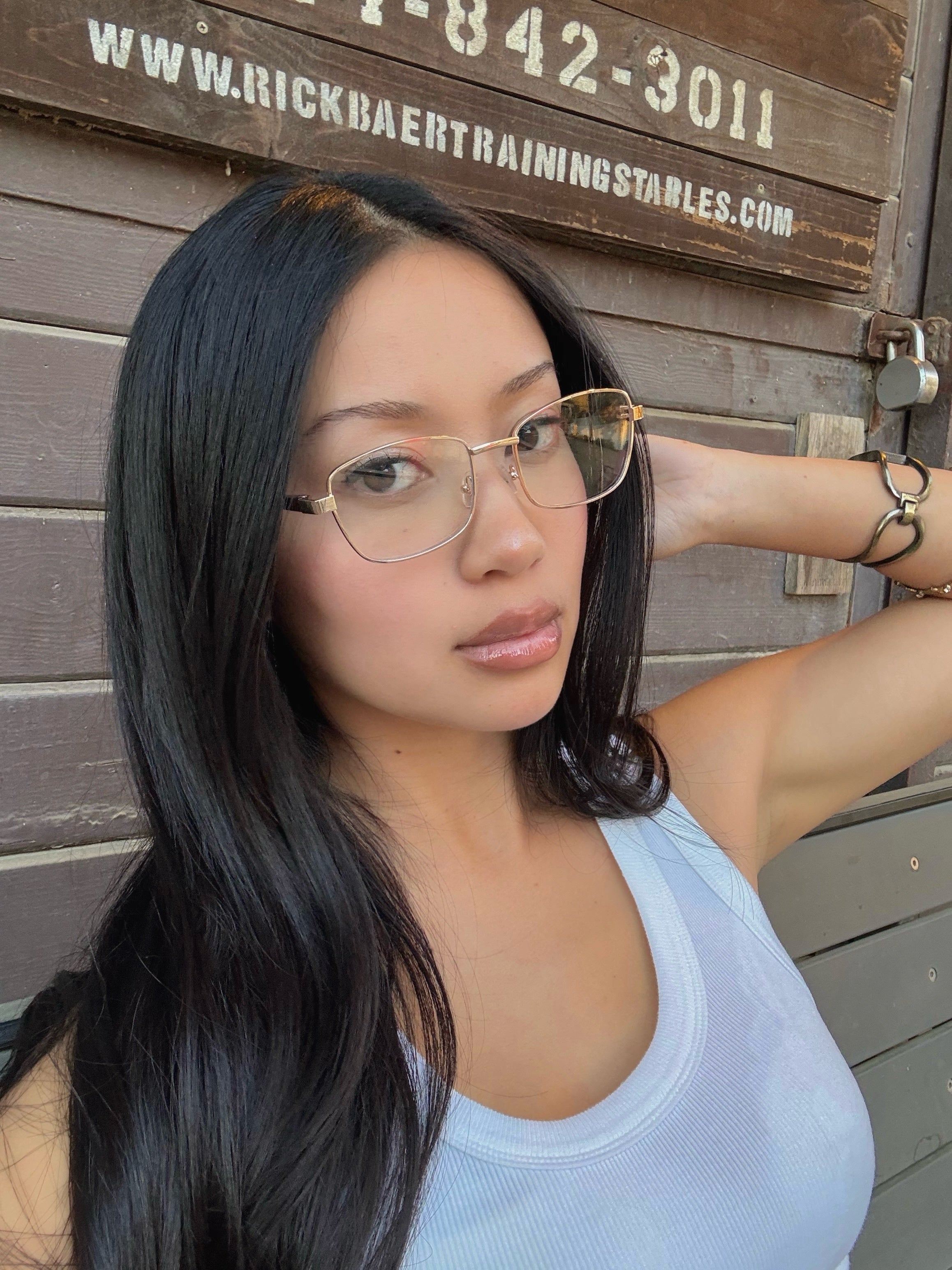 A woman taking a selfie with gold metal frame glasses with cat eye lenses